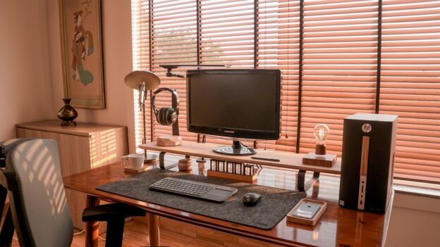 a computer desk with a monitor, keyboard and speakers